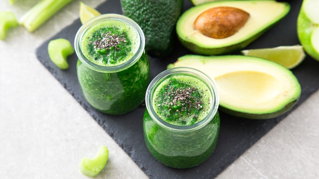 الصورة 2: Green avocado smoothie with chia seeds, served in glass jars beside avocado and lime slices.