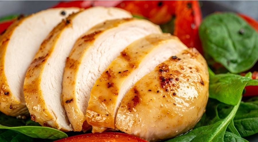 A grilled chicken breast served over a bed of steamed spinach