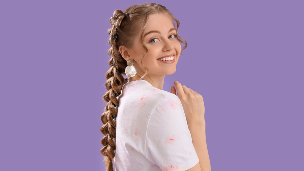 Smiling woman with a long braided ponytail against a purple studio background.
