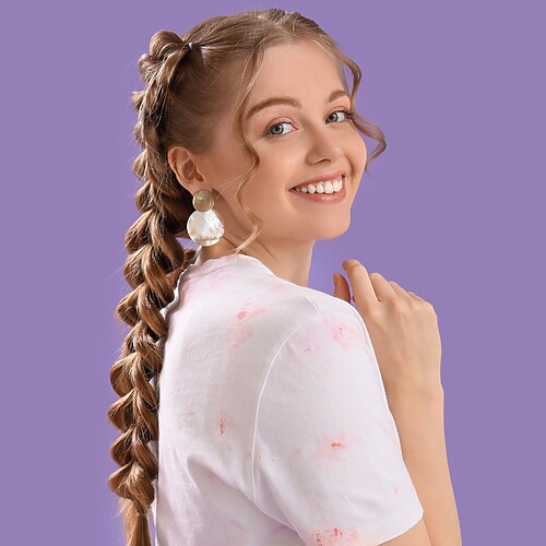 Smiling woman with a long braided ponytail against a purple studio background.