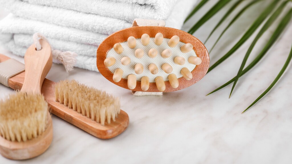 Wooden dry brushes and a massage brush placed beside folded white towels on a clean bathroom counter.