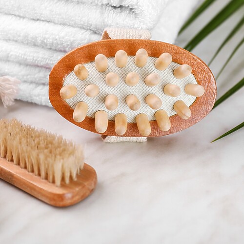 Wooden dry brushes and a massage brush placed beside folded white towels on a clean bathroom counter.