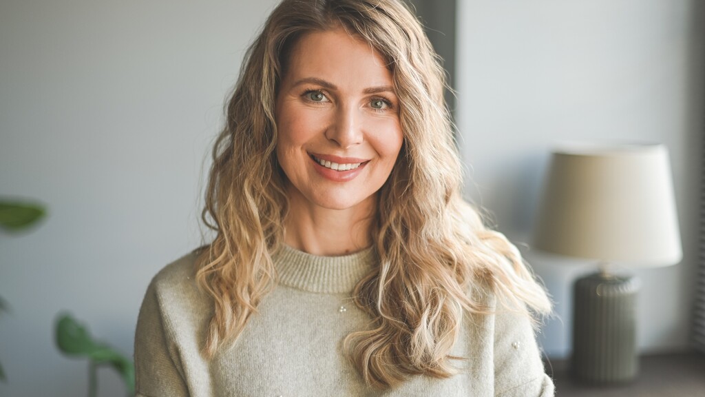 Mature woman with long blonde layered waves and soft face-framing movement.