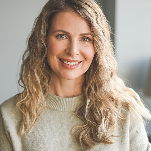 Mature woman with long blonde layered waves and soft face-framing movement.