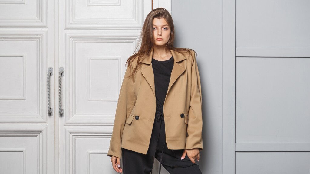 Woman wearing a tan blazer over a black outfit for a polished budget-friendly style look.