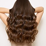 Back view of long, shiny wavy brown hair with smooth, healthy-looking ends.