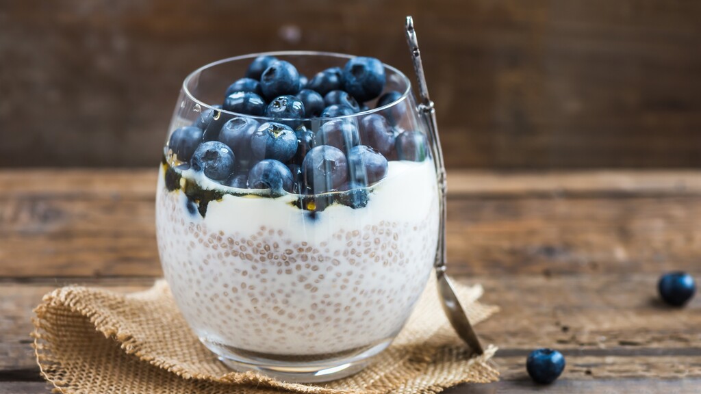 Chia seed pudding topped with blueberries in a glass cup.