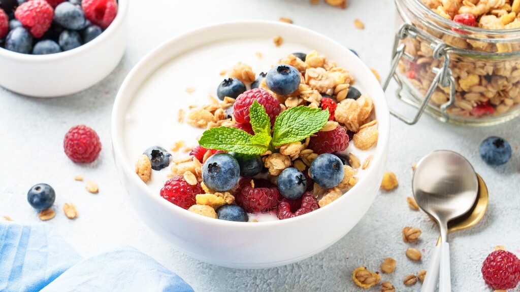 Greek yogurt bowl topped with granola, blueberries, raspberries, and mint.