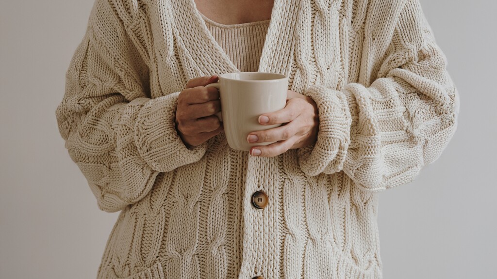 Close-up of a cream knit cardigan with a classic button detail and neutral styling.