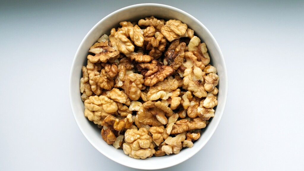 Bowl of shelled walnuts on a simple light background.