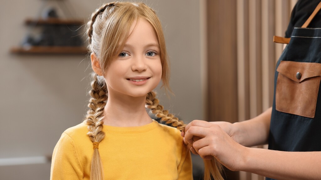 Tween girl with double braids while a stylist adjusts her hair for an easy school morning hairstyle.