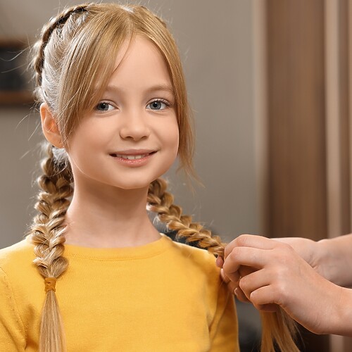 Tween girl with double braids while a stylist adjusts her hair for an easy school morning hairstyle.