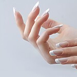 Close-up of hands with long square French tip nails on a soft gray background.