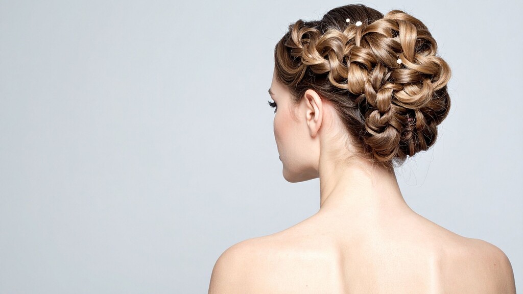Intricate braided updo hairstyle with pinned curls, shown from the side back.