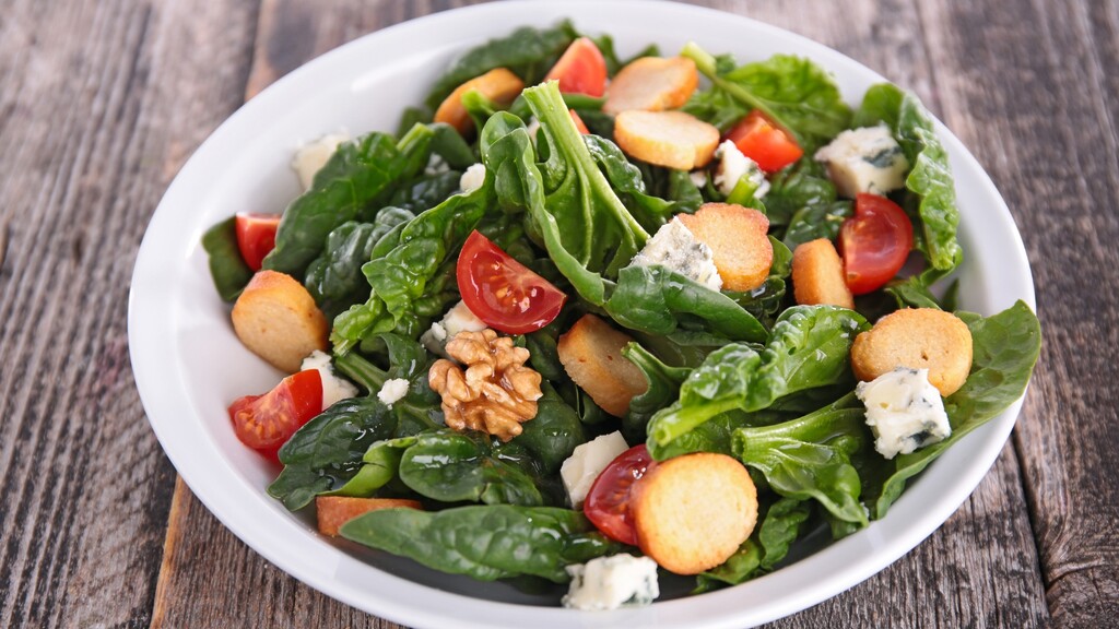 Spinach salad with walnuts, cherry tomatoes, croutons, and cheese.