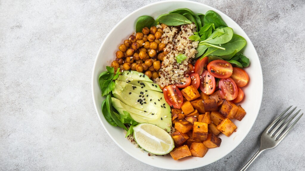 A balanced quinoa bowl with chickpeas, sweet potatoes, avocado, spinach, and tomatoes, showing fiber-rich carbs for steady blood sugar.
