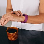 Woman checking her smartwatch beside a cup of black coffee during a morning fasting routine.