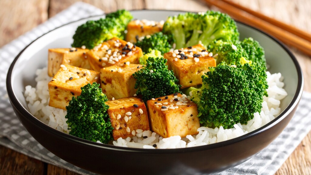 Broccoli florets served with tofu cubes and rice in a bowl.