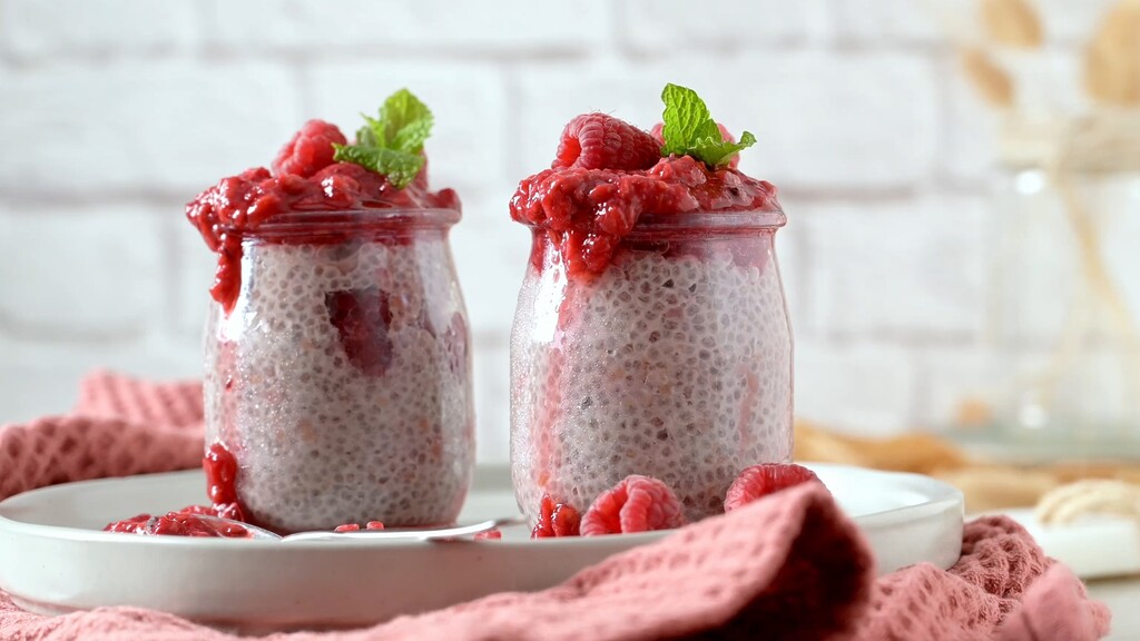 Chia seed pudding jars topped with raspberry compote and fresh mint.