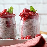 Chia seed pudding jars topped with raspberry compote and fresh mint.