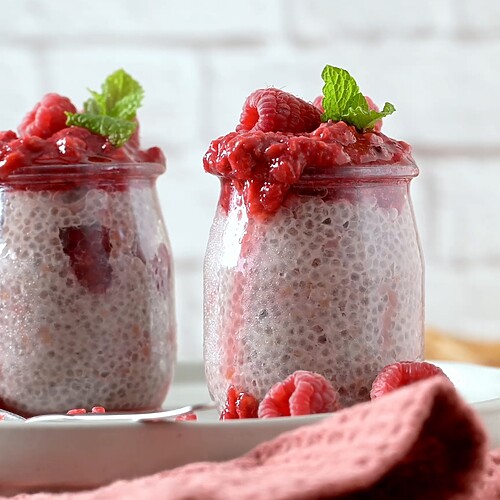 Chia seed pudding jars topped with raspberry compote and fresh mint.