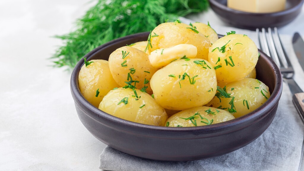 Boiled baby potatoes topped with fresh herbs in a bowl, illustrating a diabetes-friendly way to prepare starchy vegetables.
