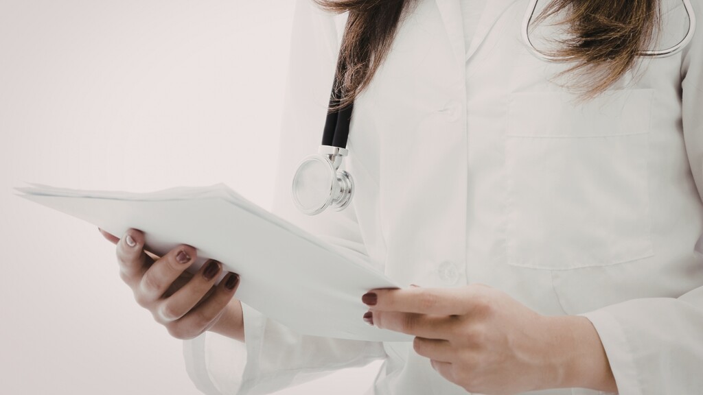 Doctor holding patient records with a stethoscope around her neck.