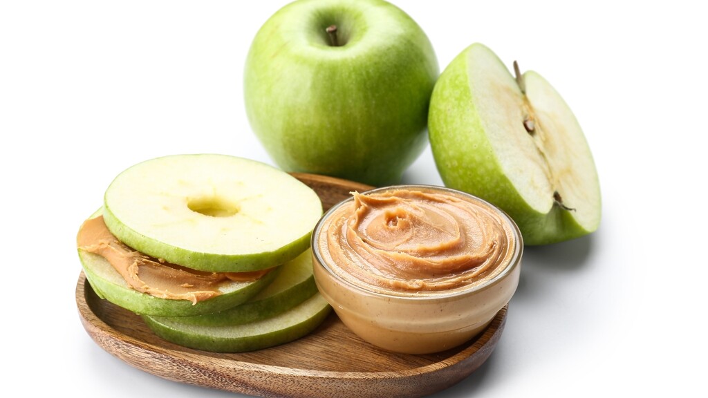 Green apple slices served with a small bowl of peanut butter.