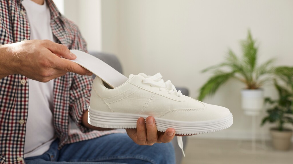 A person checks the inside of a white shoe before wearing it as part of diabetic foot care.