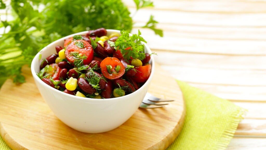 Kidney bean salad with tomatoes, corn, and fresh herbs served in a white bowl.