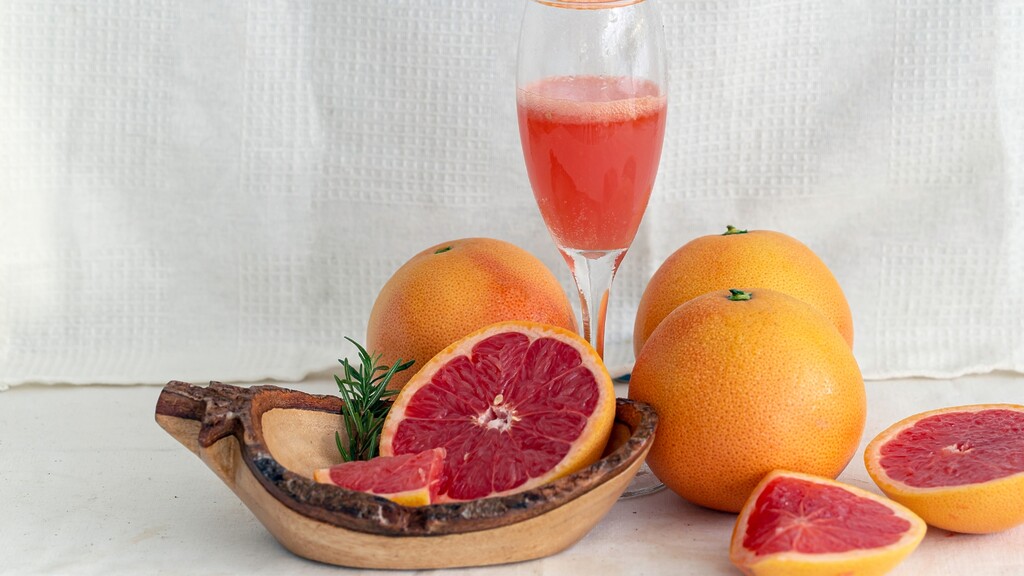 Ruby red grapefruit halves and grapefruit juice served beside whole grapefruits.