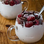 11 Low-Carb Snacks for Weight Loss That Beat Night Cravings Frozen raspberries with cream and dark chocolate shavings served in small glass cups on a wooden table.