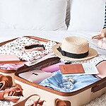 Open suitcase packed with travel clothes and a clear toiletry pouch, showing organized travel preparation.