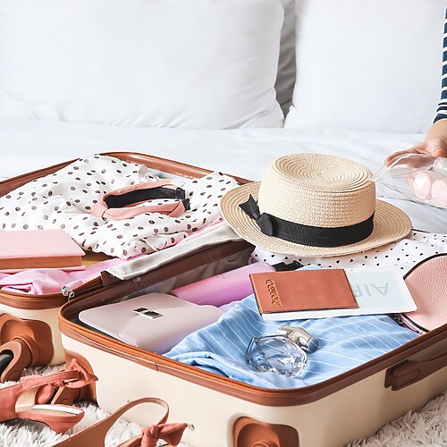 Open suitcase packed with travel clothes and a clear toiletry pouch, showing organized travel preparation.