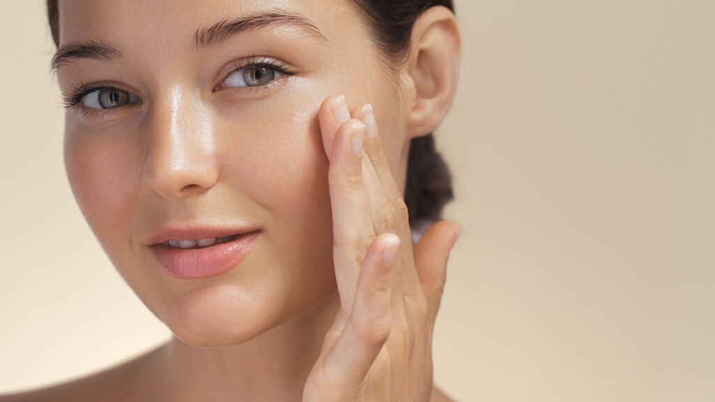 Woman gently touching her cheek to show hydrated, healthy-looking skin.