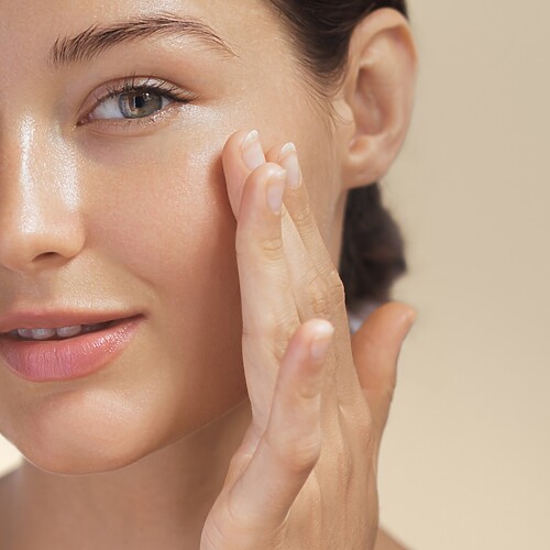 Woman gently touching her cheek to show hydrated, healthy-looking skin.