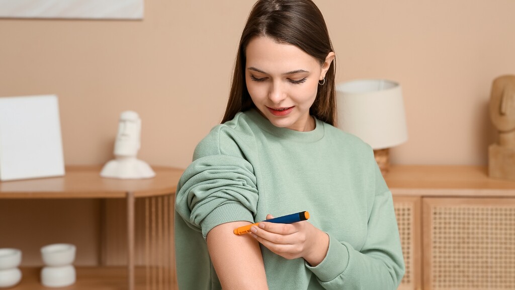 Woman using an insulin pen on her upper arm while preparing to manage diabetes during travel.