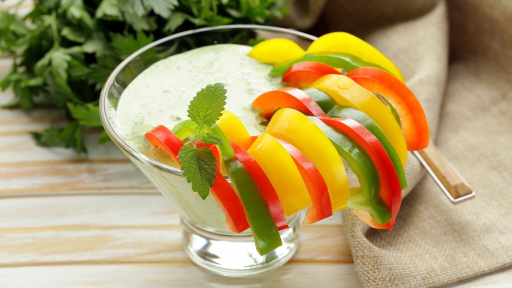 Sliced red, yellow, and green bell peppers served with a creamy herb yogurt dip.