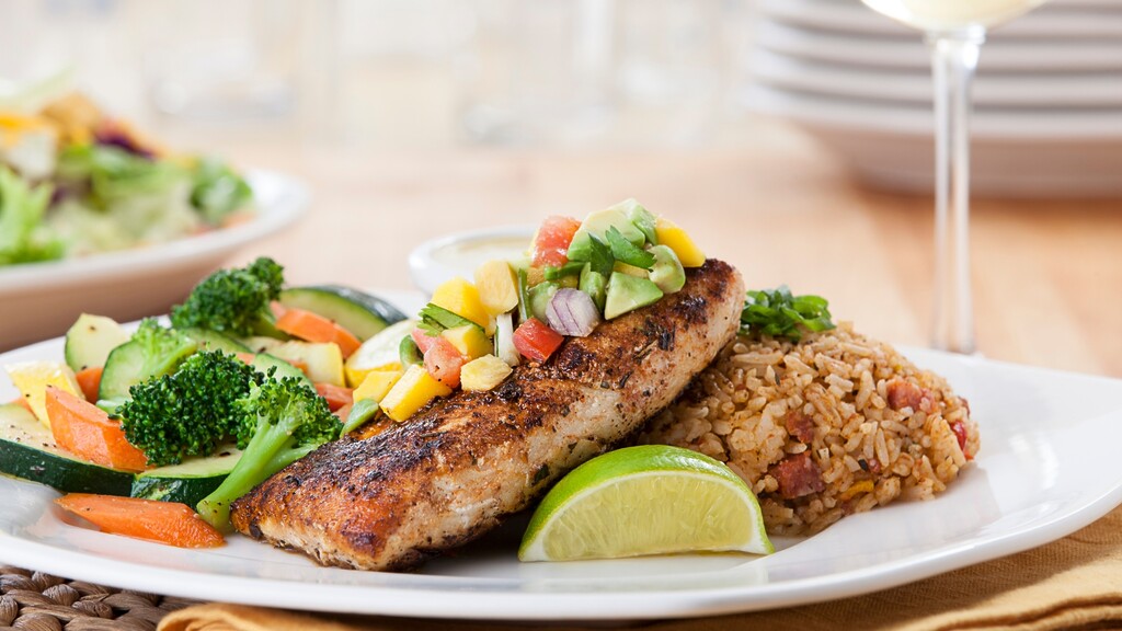 Grilled fish served with vegetables, rice, and a lime wedge.