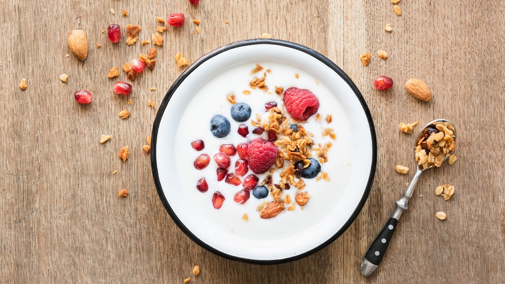 Plain Greek yogurt topped with berries, pomegranate seeds, granola, and almonds.