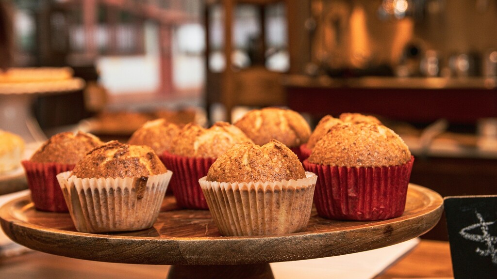 Freshly baked muffins on a wooden cake stand, showing browned tops and paper liners