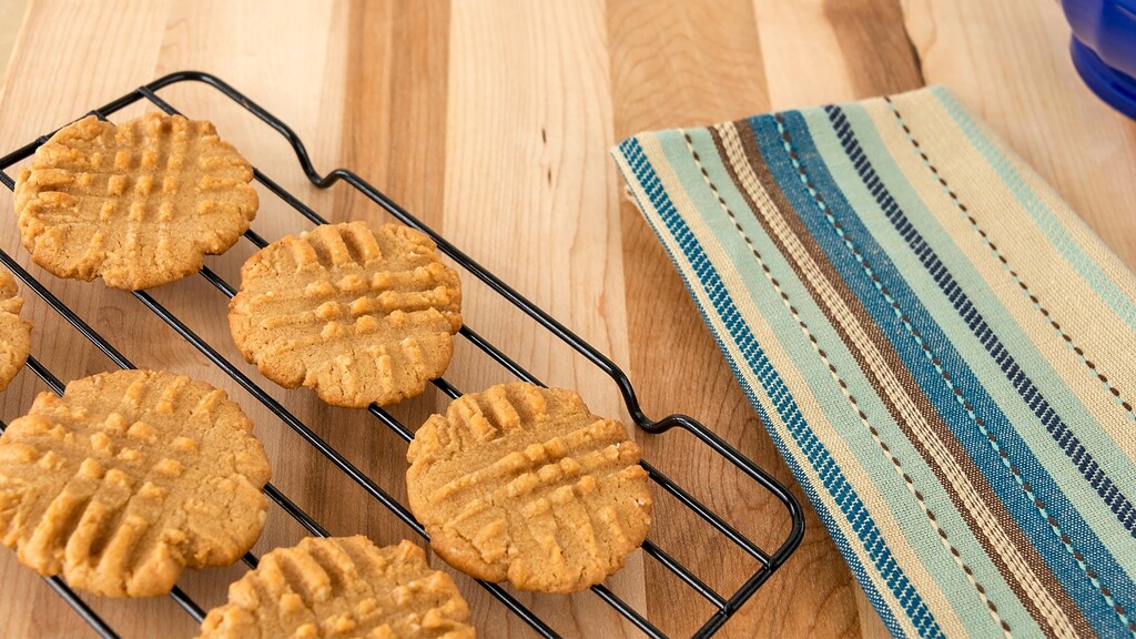 Crispy homemade cookies cooling on a wire rack on a wooden kitchen counter.