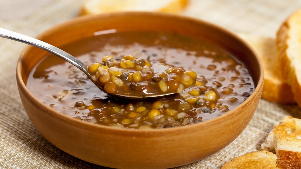 Warm lentil soup in a wooden bowl with a spoon.
