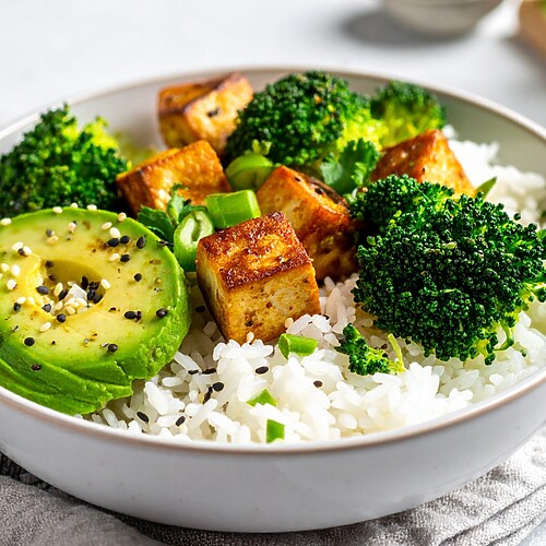 Tofu rice bowl with broccoli, avocado, sesame seeds, and green onions.