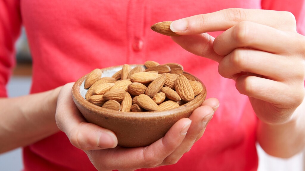 Hands holding a small bowl of almonds as a light bedtime snack for stable blood sugar.