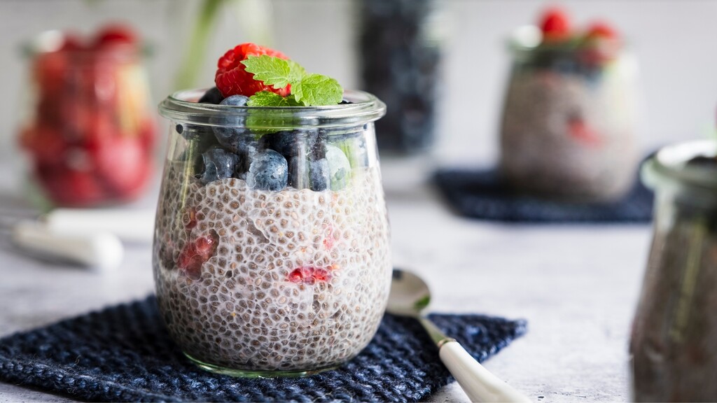 Chia seed pudding in a glass jar topped with blueberries, raspberries, and fresh mint.