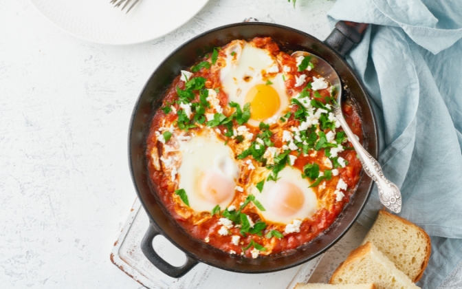 Shakshuka with poached eggs in tomato sauce in a skillet.
