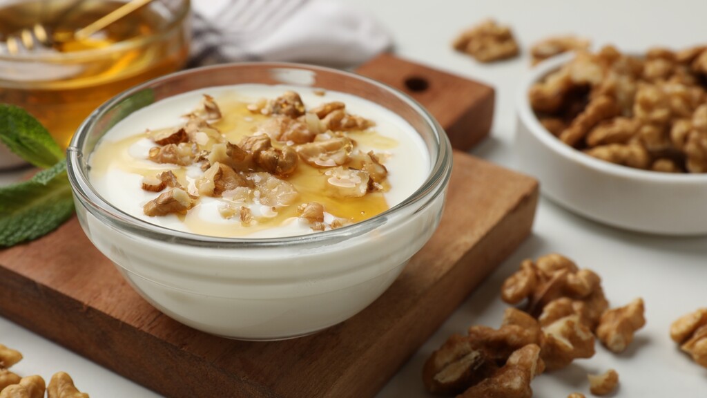 Greek yogurt topped with crushed walnuts in a glass bowl.