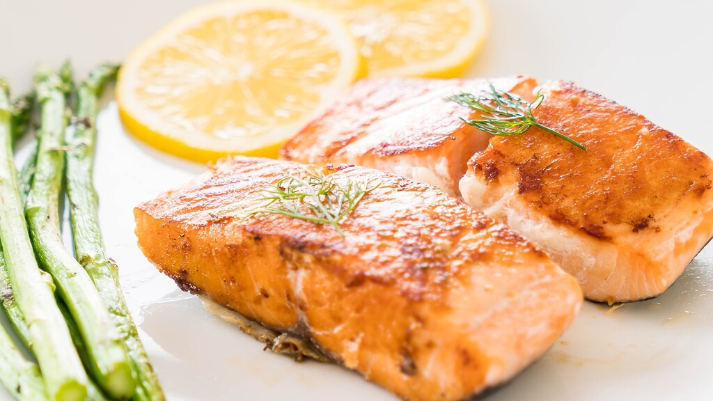 Seared salmon fillets served with asparagus and lemon slices.
