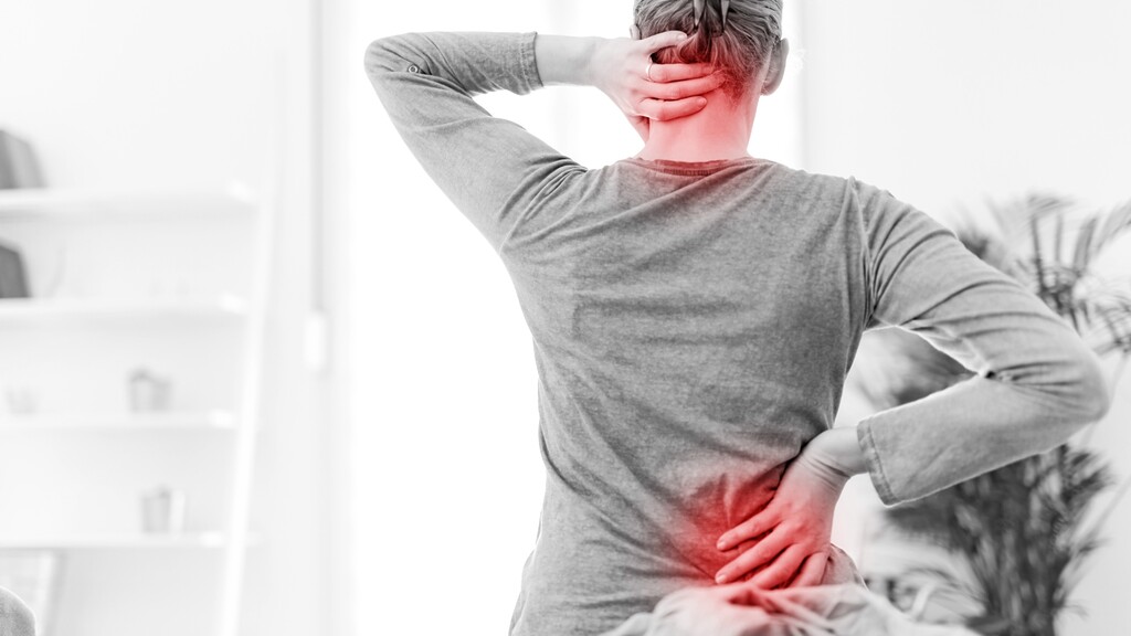 A person holding their neck and lower back with red pain highlights, showing neck and back pain from muscle tension.